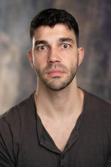 Obraz premium Handsome caucasian white male with black short hair and stubble with brown t shirt, looking surprised