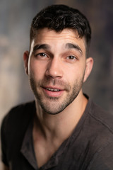 Fototapeta premium Handsome caucasian white male with black short hair and stubble with brown t shirt, looking smug
