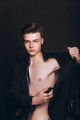 Handsome shirtless man putting deodorant. image of young man using deodorant isolated - Image. Handsome young man with deodorant on dark background - Image