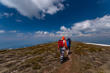 Mountaineers hiking in the mountains in cloudy weather, panorama of dramatic blue sky with white clouds	