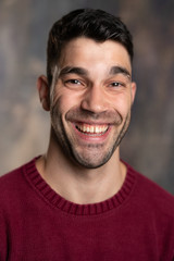 Fototapeta premium Handsome caucasian white male with black short hair and stubble and burgundy sweater jersey cheesy grin