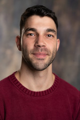 Handsome caucasian white male with black short hair and stubble and burgundy sweater jersey