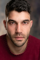 Handsome caucasian white male with black short hair and stubble and burgundy sweater jersey, tough