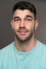 Fototapeta premium Handsome caucasian white male with black short hair and stubble with light blue t shirt