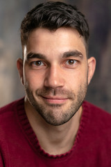 Handsome caucasian white male with black short hair and stubble and burgundy sweater jersey, silly face