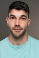 Fototapeta premium Handsome caucasian white male with black short hair and stubble with light blue t shirt