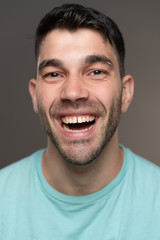 Obraz premium Handsome caucasian white male with black short hair and stubble with light blue t shirt smiling