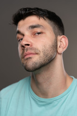 Handsome caucasian white male with black short hair and stubble with light blue t shirt