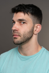 Fototapeta premium Handsome caucasian white male with black short hair and stubble with light blue t shirt