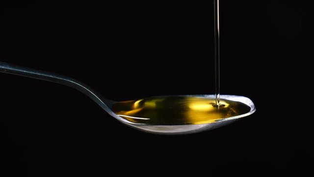 Draining Extra Virgin Olive oil over a tablespoon in slowmotion