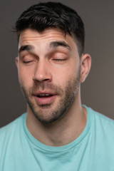 Obraz premium Handsome caucasian white male with black short hair and stubble with light blue t shirt eyes closed