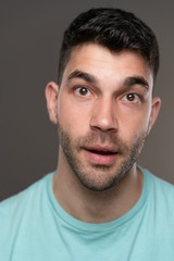 Fototapeta premium Handsome caucasian white male with black short hair and stubble with light blue t shirt shocked