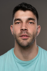 Fototapeta premium Handsome caucasian white male with black short hair and stubble with light blue t shirt