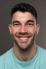 Obraz premium Handsome caucasian white male with black short hair and stubble with light blue t shirt