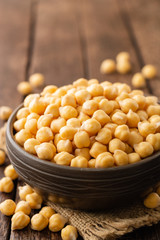 Chickpeas in ceramic bowl on dark wooden rustic table. Selective focus.