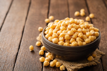 Chickpeas in ceramic bowl on dark wooden rustic table. Selective focus.