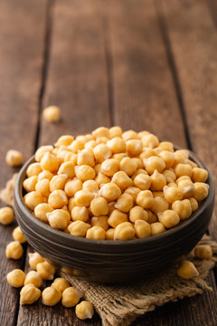 Chickpeas in ceramic bowl on dark wooden rustic table. Selective focus.