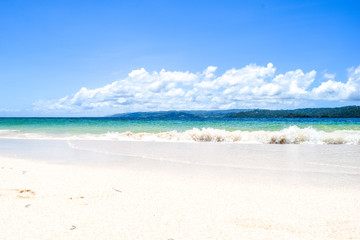 Caribbean island white beach with blue turquoise ocean and waves, blue sky with some clouds, paradise island at cayo levantado
