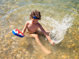 happy child playing with a toy ship in the sea