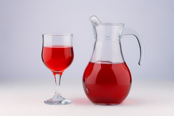 Glass and jug with a cool sweet drink from the juice of berries or fruits, diluted with water