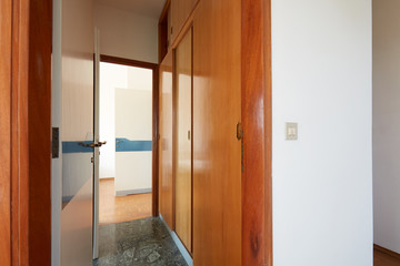 Corridor with wooden wardrobe and open door, interior in country house