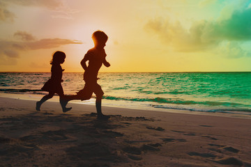 little boy and girl run play at sunset tropical beach