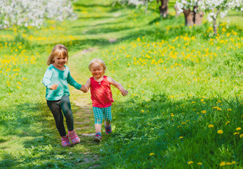 happy girls play run in spring nature, apple blossom, seasonal activities