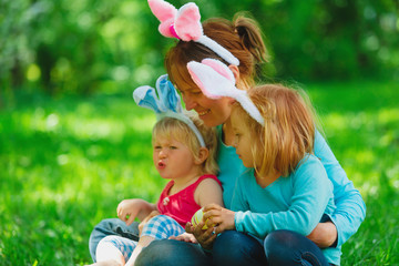 happy mom and kids on easter eggs hunt in spring