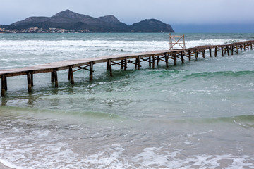 Steg am Strand wird von grün blauen Wellen umspült, copy space unten