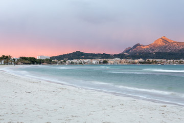 Rot orangener Sonnenuntergang am weißen Strand mit Blick auf die Berge am Horizont