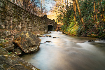 Stream flowing under a stone bridge in the forest.  Long exposure stream in a national forest.