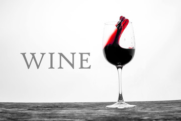Red wine in the glass splashes in motion on a white background. Design drink card with text