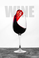 Red wine in the glass splashes in motion on a white background. Stylish design card with text