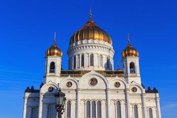 Fototapeta na wymiar Walls and golden domes of Cathedral of Christ the Saviour against blue sky in sunny spring morning