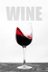 Red wine in the glass splashes in motion on a white background. Stylish design card with text