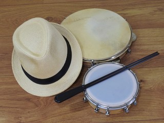 A samba player (sambista) hat and two Brazilian percussion musical instruments: pandeiro (tambourine) and tamborim with drumstick. The instruments are widely used to accompany samba music.
