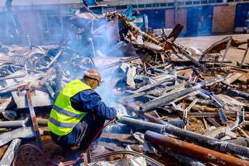 Worker is cutting scrap metal with acetylene torch