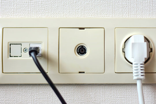 Electrical sockets on the wall with black connection internet plug and white wire. Socket set with usb cord and electricity cable with selective focus on neutral background. 