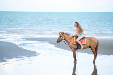 Pretty young lady riding a horse on the beach background of the sea