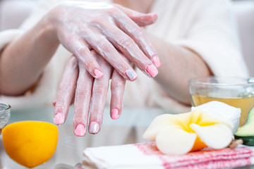 Obraz na płótnie Canvas Woman applying the cream on hands moisturizing and nourishing them with natural cosmetics. Hygiene and care for the skin