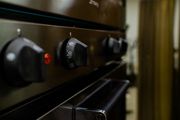 Close up of oven knob on metal board dial of a stainless steel electric oven