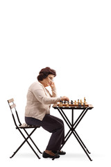 senior woman with a chessboard at a table looking at the chess figure and thinking