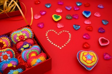 Knitted hearts in a gift box on a red background. Valentine's Day, love, handmade, amigurumi, hobby, decoration, greeting card, creative.