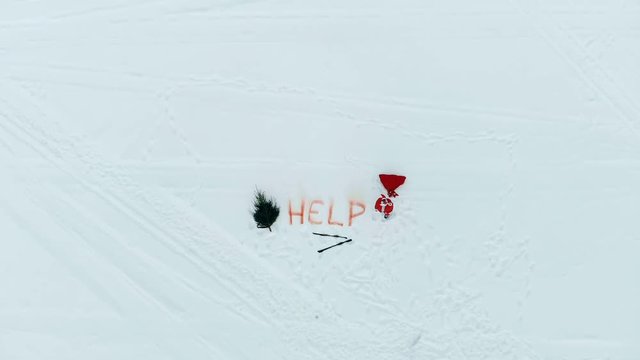 Snowy field with axed fir tree, skis and Santa Claus shouting for help