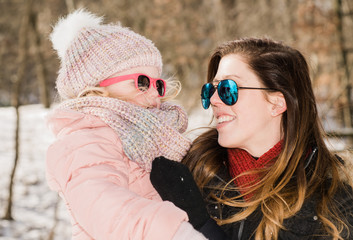 Mother holding daughter out in the snow