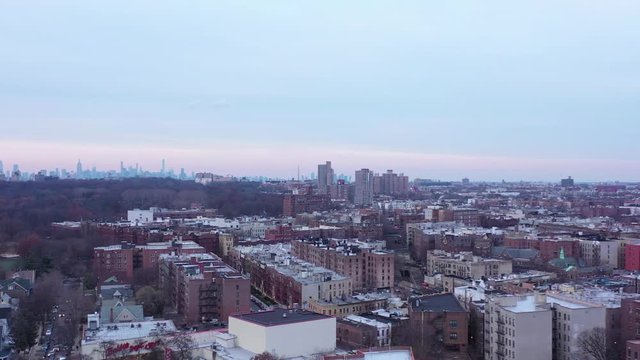 Drone rise over central Brooklyn, New York, just before sunset, revealing the Manhattan skyline in the distance.  in 4K.