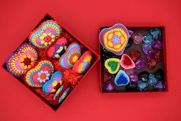 Knitted hearts in a gift box on a red background. Handmade, amigurumi hobby, love, Valentine's Day, decoration, design.