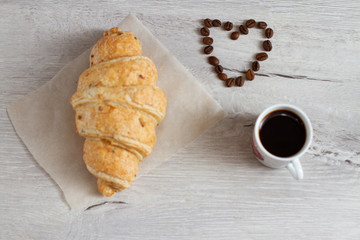 cup of coffee and croissant on wooden table