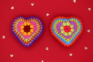 Knitted hearts on a red background. Handmade, amigurumi hobby, love, Valentine's Day, decoration, design.