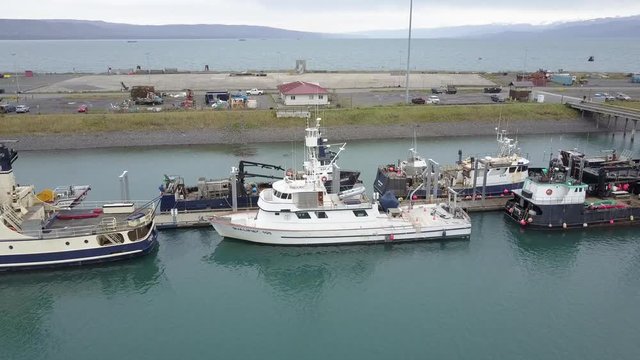 Aerial shot flying over large commercial fishing boats docked in the harbor of Homer, Alaska USA